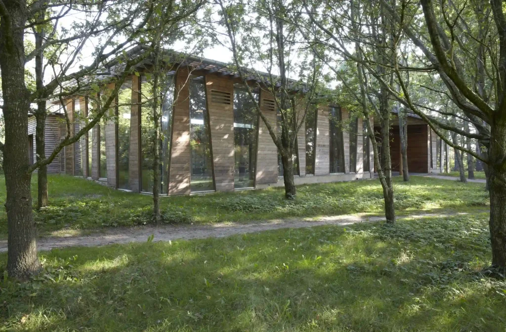 Arkitektonisk bygning med store glasflader, der smelter sammen med den omgivende skov og natur
